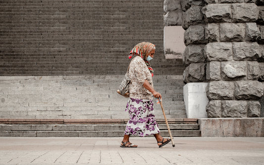 woman in brown and white floral dress walking on sidewalk during daytime