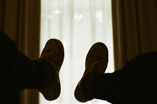 person wearing brown shoes near white curtain
