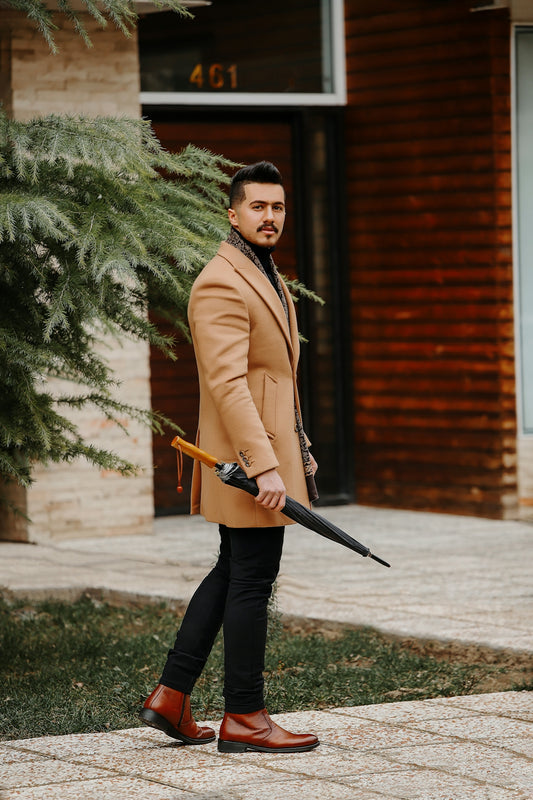 a man in a tan coat holding a black umbrella