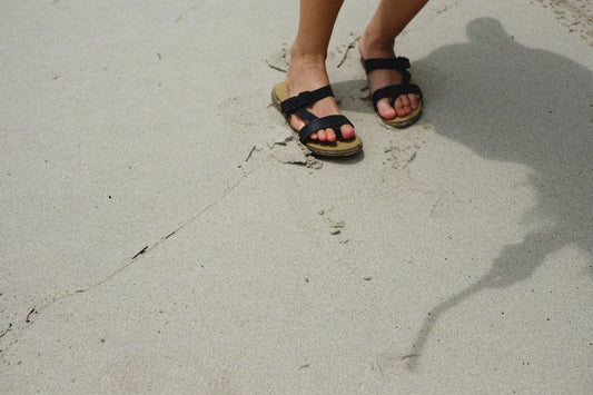 a person wearing sandals standing on a sidewalk