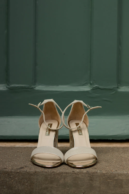 a pair of white high heeled shoes sitting on the ground