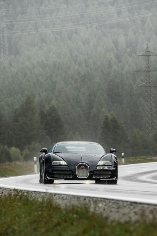 a bugatti driving on a road in the rain