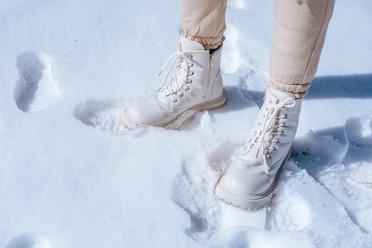 a person wearing white boots standing in the snow