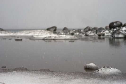 a small rock sitting on top of a beach covered in snow