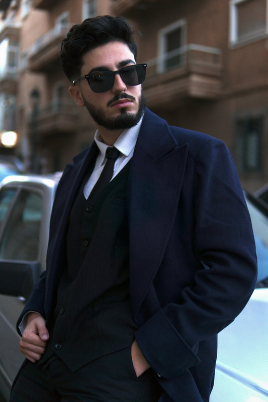 a man in a suit and sunglasses standing in front of a car
