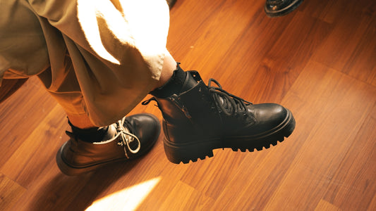 A person standing on a wooden floor wearing black boots