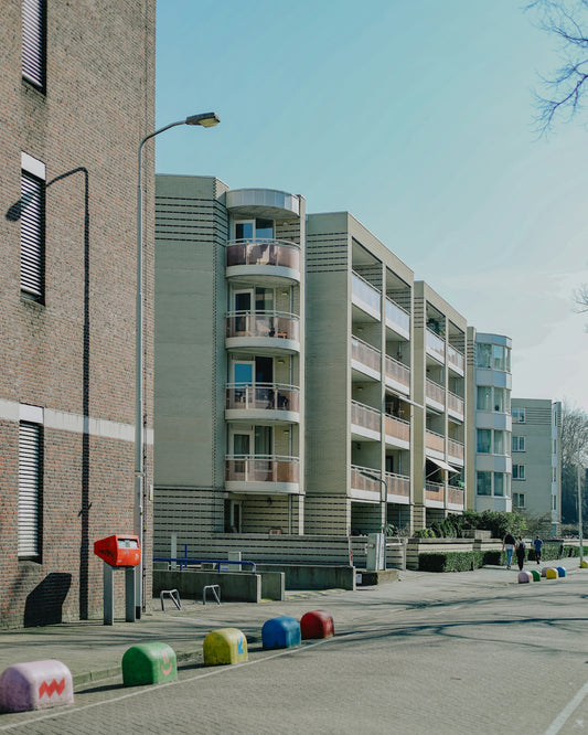 Apartment buildings line a quiet, sunny street.