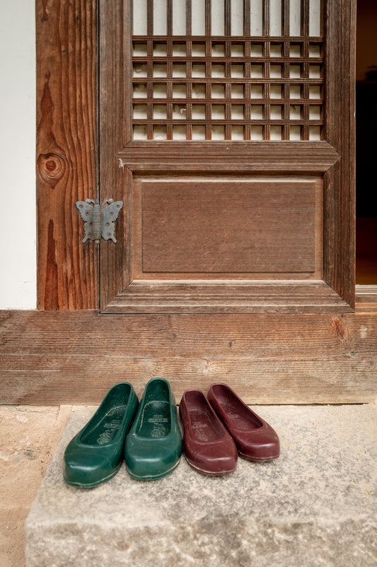 Shoes sit outside a traditional wooden door.