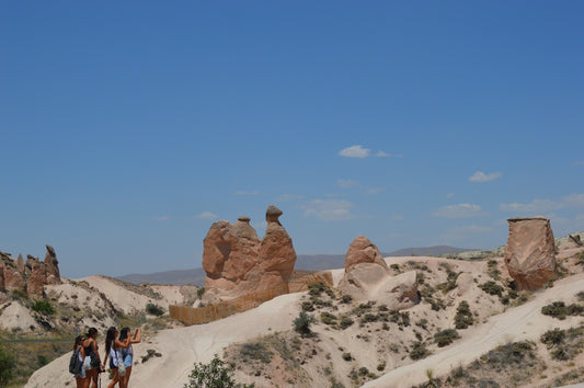 People explore unique rock formations under a blue sky.