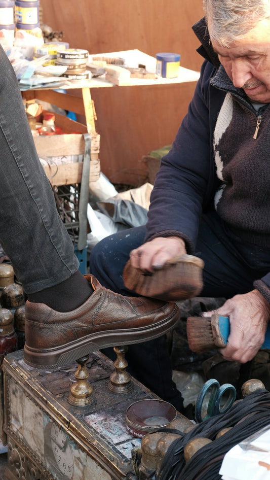 A shoe shiner is polishing a customer's shoe.