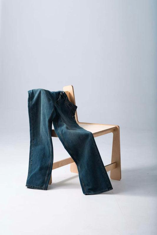 Jeans casually draped over a simple wooden chair.