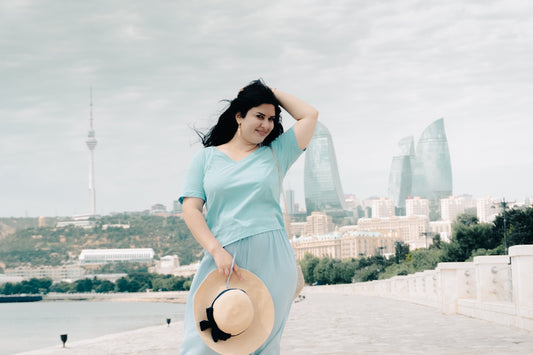 Woman holding a hat with a modern city skyline.