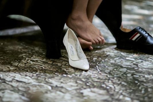 White high heel, bare foot, and black man's dress shoe
