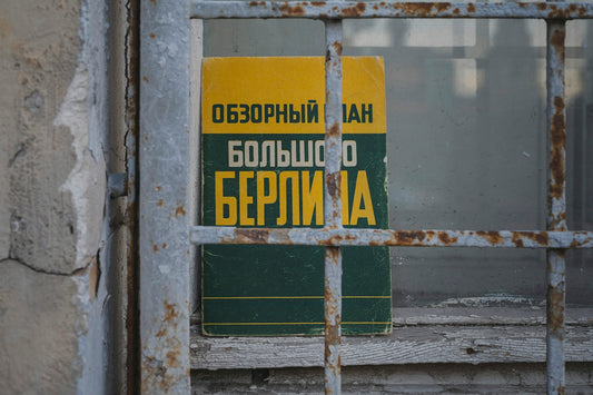 A vintage book with yellow and green cover behind a rusty metal grate